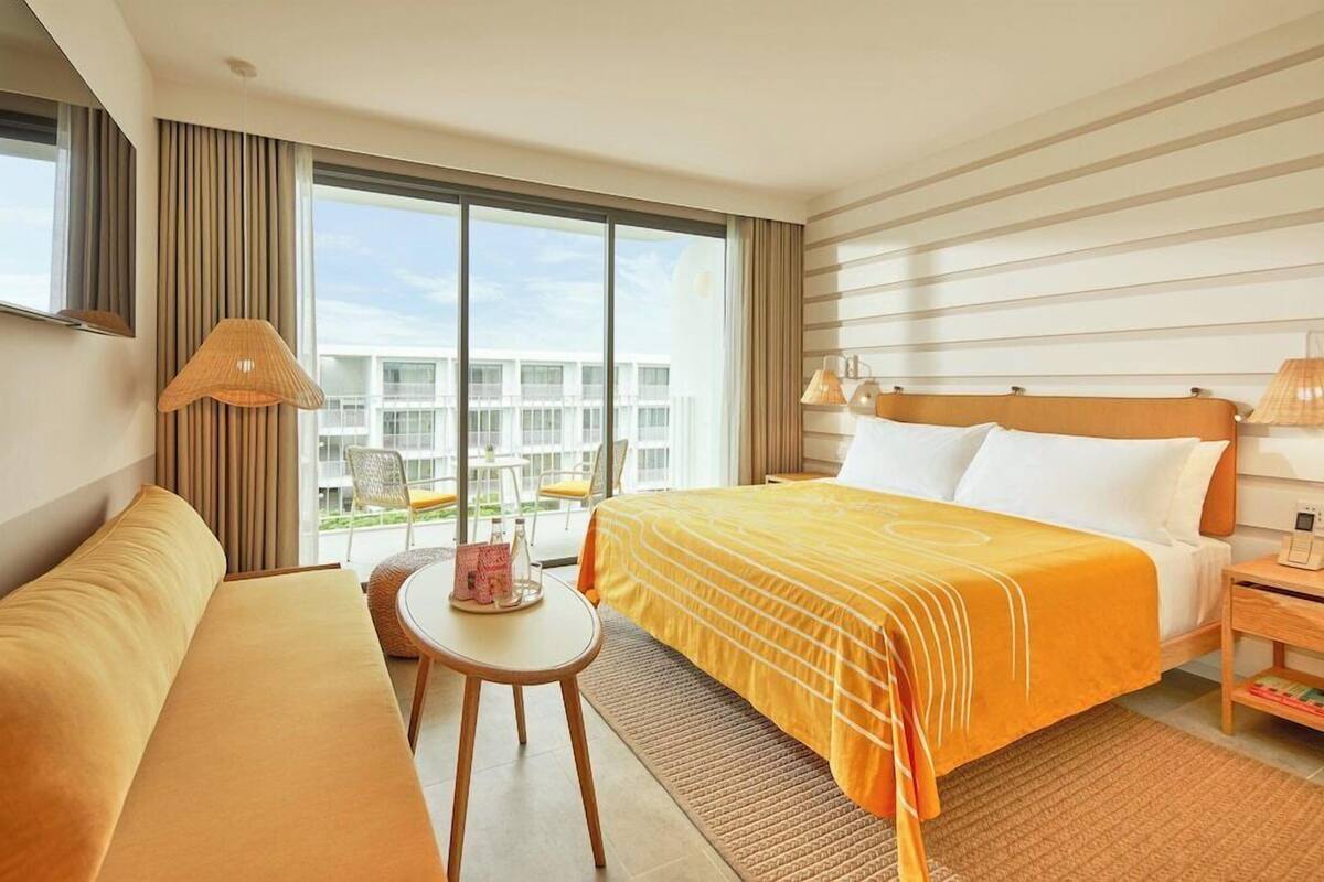 Ein Hotelzimmer mit Bett, Sofa, kleinem Tisch und Lampe.