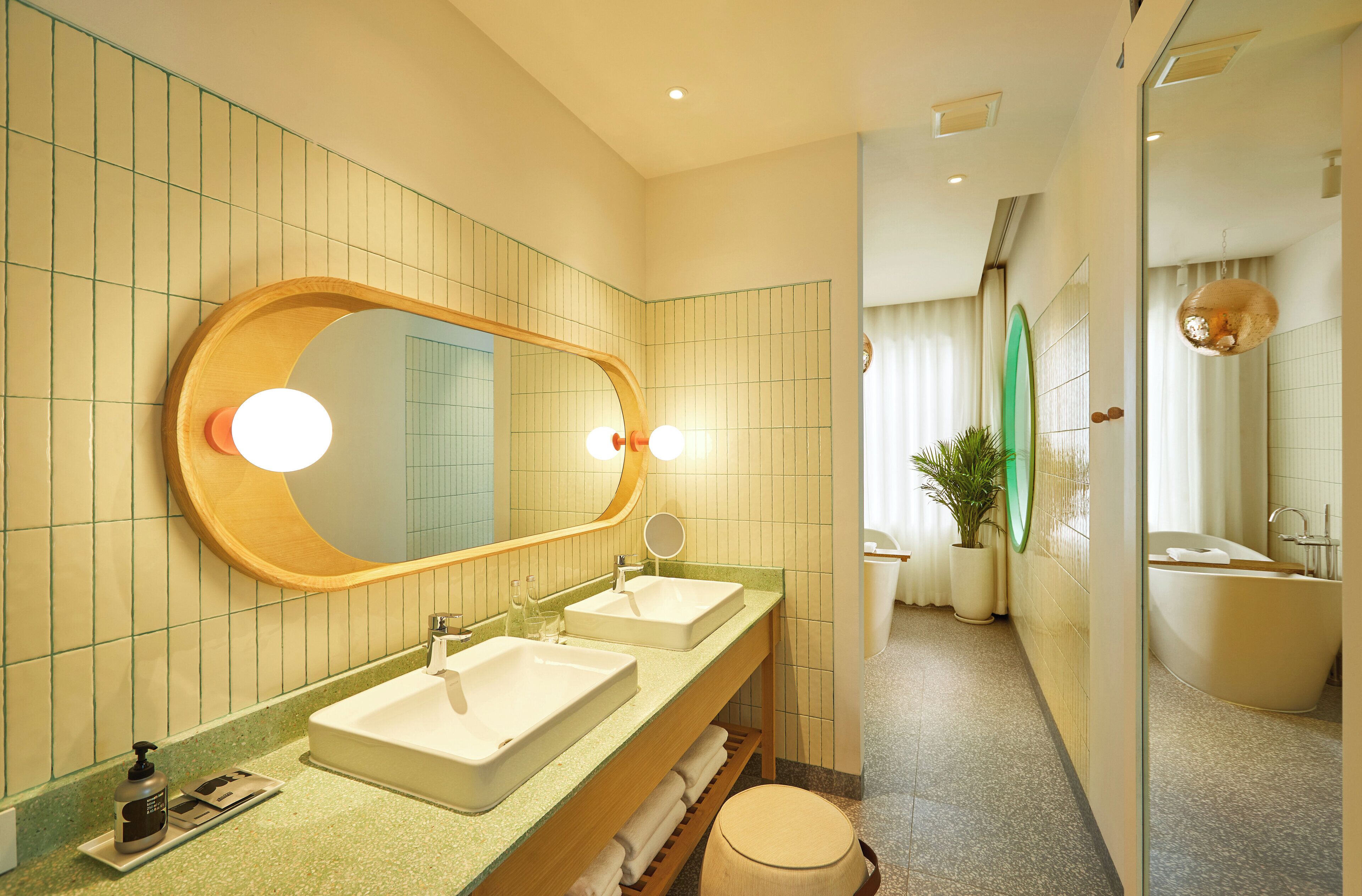 A modern bathroom with two sinks, a large mirror, and a bathtub.
