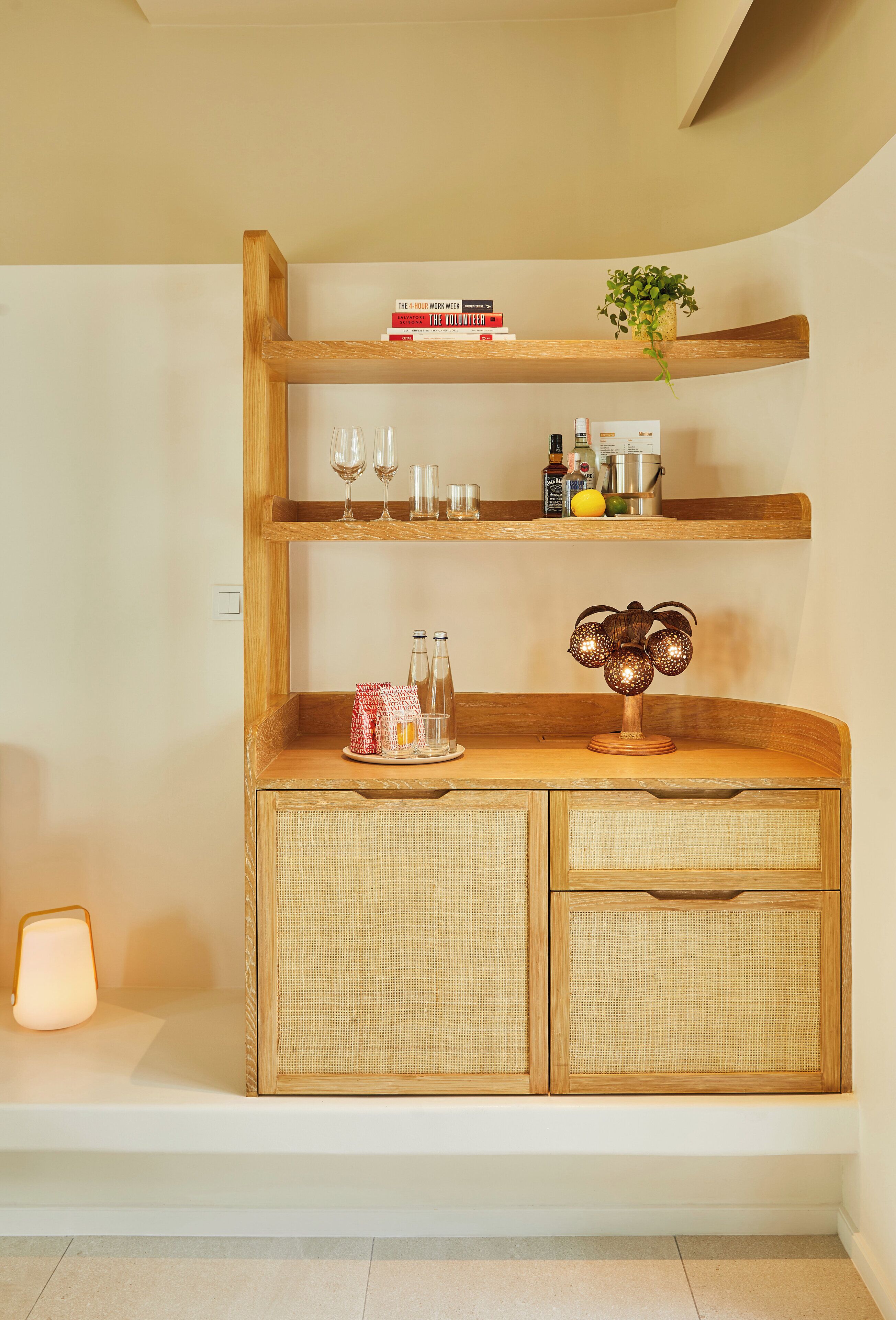 Ein Holzregal mit Büchern, Gläsern und einer dekorativen Lampe.