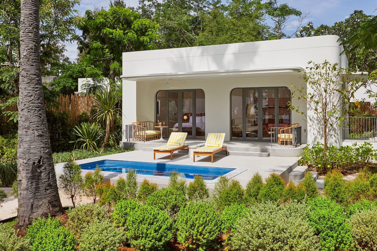 Ein modernes Haus mit Schwimmbad, zwei Liegestühlen und einer überdachten Terrasse.