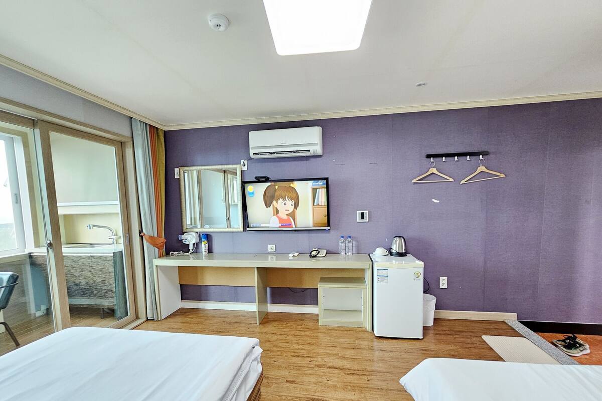 A hotel room with a bed, a desk, a TV, and a window.