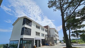 A two-story building with a modern design, featuring large windows and a stone-paved entrance area. - Haemil Resort (Jeju City)