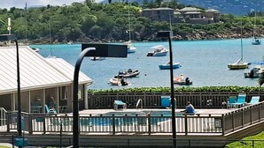 Zona de piscina con sillones de descanso y vistas al mar con barcos.