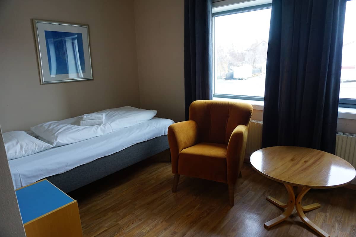A room with a bed, a chair, and a table.