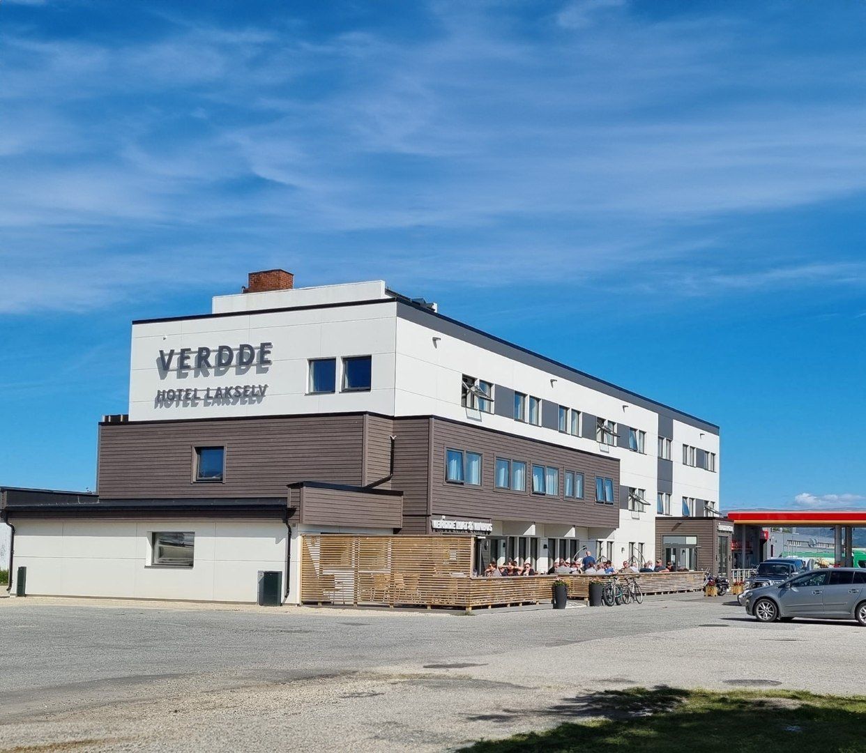 Moderni hotellirakennus nimeltä VERDE HOTEL LAKSELVY, jossa on tasakatto, useita ikkunoita ja selkeästi näkyvä ulkotila, joka on tarkoitettu oleskeluun.
