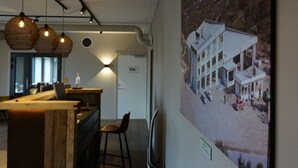 A modern interior with a wooden bar area, pendant lighting, and a large framed photograph of a building on the wall. - Verdde Hotel Lakselv (Porsanger)