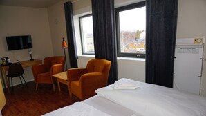A hotel room with a bed, two orange chairs, a desk, a television, and a window with curtains. - Verdde Hotel Lakselv (Porsanger)