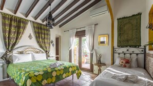 A bedroom with two beds, a green polka dot bedspread, a white bedspread, and a green tapestry on the wall. - Villa "madre tierra pool jacuzzi" with Mountain View, Pool, Whirlpool (Cómpeta)