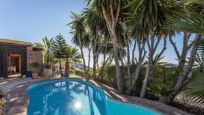 A swimming pool surrounded by palm trees and a building with a tiled exterior. - Villa "madre tierra pool jacuzzi" with Mountain View, Pool, Whirlpool (Cómpeta)