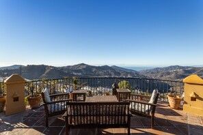 A terrace with a wooden bench, potted plants, and a view of distant hills. - Villa "madre tierra pool jacuzzi" with Mountain View, Pool, Whirlpool (Cómpeta)