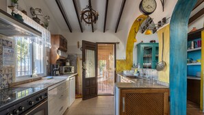 A kitchen with a stove, microwave, and wooden cabinets. - Villa "madre tierra pool jacuzzi" with Mountain View, Pool, Whirlpool (Cómpeta)