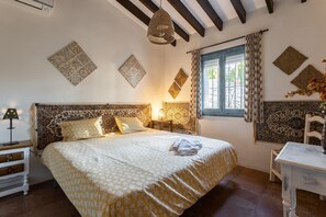 Une chambre à coucher avec un grand lit, une table de chevet, une table et une fenêtre avec des rideaux.
