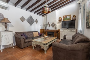 Un salon avec une cheminée, un téléviseur et une table basse à motifs.