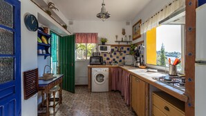 Una cocina compacta con lavadora, microondas y ventana con vistas.