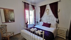 Een slaapkamer met een bed, een stoel, een nachtkastje en een decoratie aan de muur.