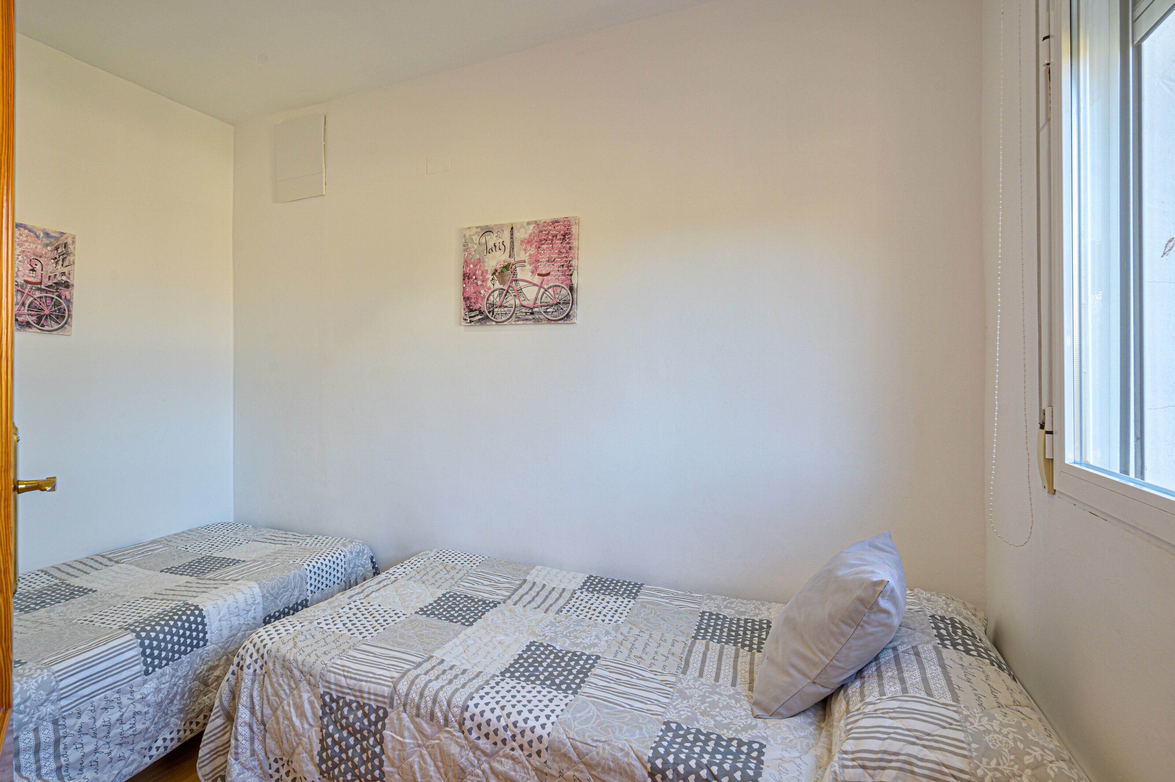 Een kamer met twee eenpersoonsbedden, een raam en twee decoraties aan de muur.
