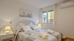 Une chambre à coucher comprenant un lit, deux tables de chevet, une œuvre d’art accrochée au mur et une fenêtre.