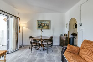 A dining area with a round table, chairs, a painting on the wall, and a sofa.