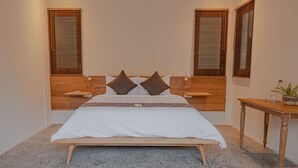 Ein Schlafzimmer mit einem hölzernen Bettgestell, weißer Bettwäsche, zwei Nachttischen, einem Holztisch und einer Topfpflanze.