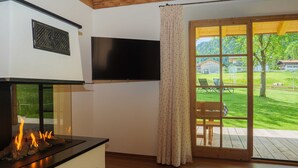 Una sala de estar moderna con chimenea, televisor de pantalla plana y puerta corrediza de vidrio que da a un patio exterior.