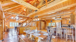 Un intérieur de chalet en bois spacieux, comprenant une grande table à manger, un coin bar et une cuisine.