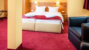 Habitació d'hotel amb un llit, taules de nit, un escriptori i una cadira.