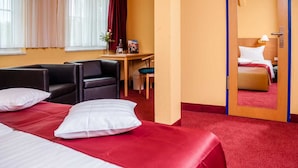 A hotel room with two beds, a desk, a chair, and a mirror.