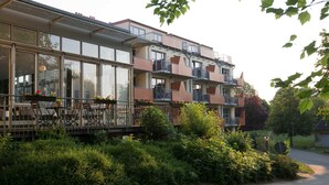 A multi-story residential building with balconies, large windows, and a garden area.