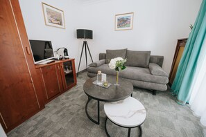 Un salon avec un canapé, une table basse, un téléviseur et une lampe.
