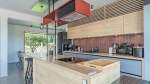 Une cuisine moderne avec un îlot central, des meubles en bois et une hotte de cuisine rouge.