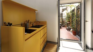 Et kompakt køkken med en gul bordplade og en skydedør, der fører til en patio med plantekasser.