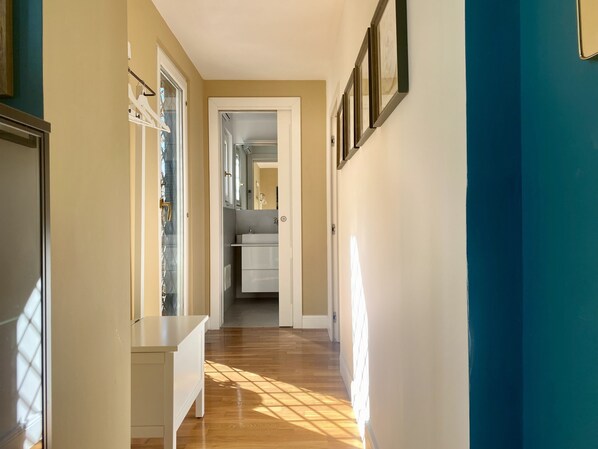 A hallway with wooden flooring, a bench, and a doorway leading to a bathroom. - The Nest Chiaia Naples | Terrace, Work & Retreat (napoli)