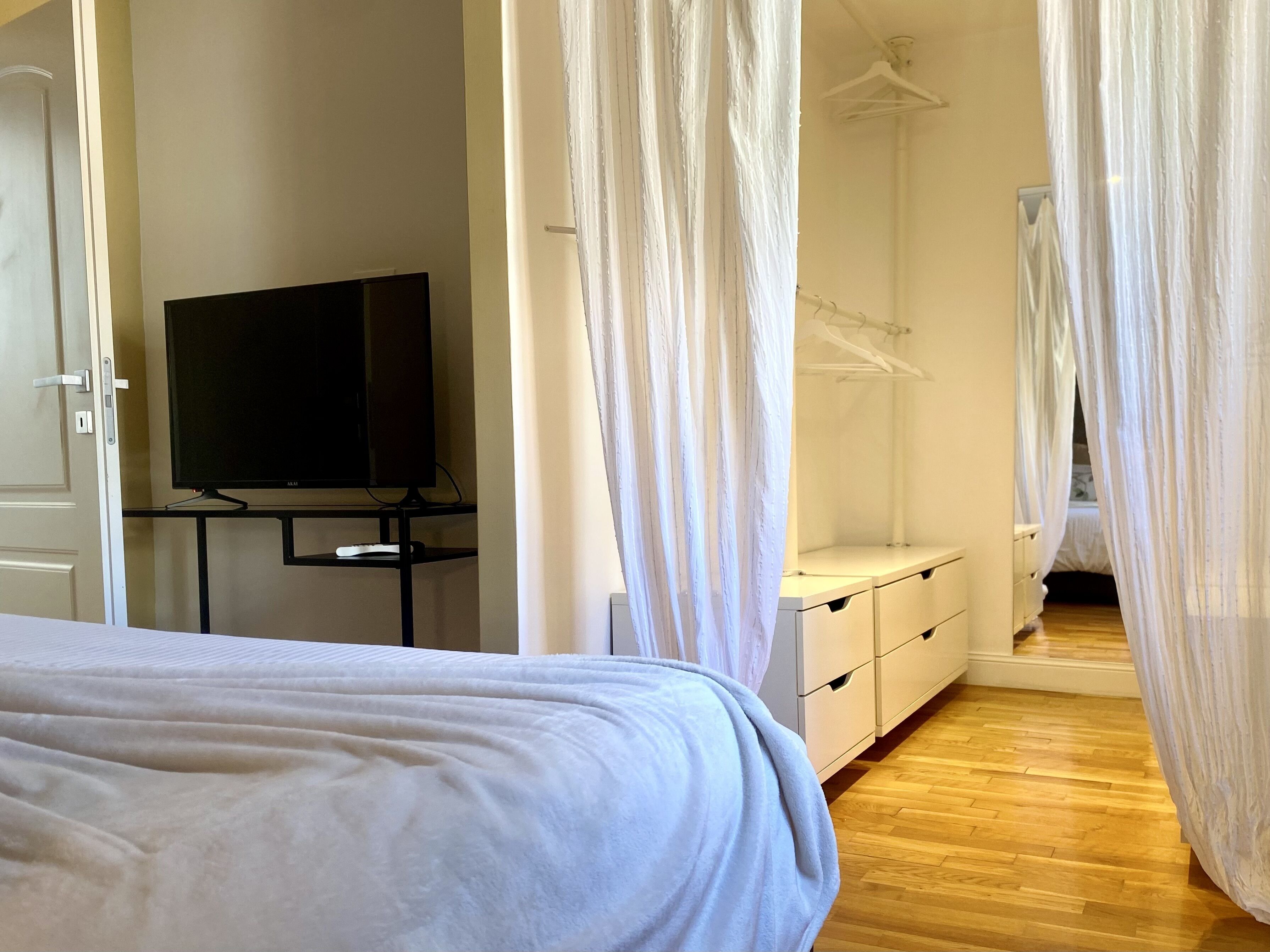 Ein Schlafzimmer mit einem Bett, einem Fernseher auf einem Schrank, einem Kleiderschrank und einem Hängeschrank.