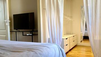 Ein Schlafzimmer mit einem Bett, einem Fernseher auf einem Schrank, einem Kleiderschrank und einem Hängeschrank.