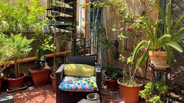 En terrasse med en fletsofa, plantekasser og et bambushegn.