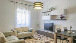 Moderni olohuone, jossa on sohva, ruokapöytä ja televisio.