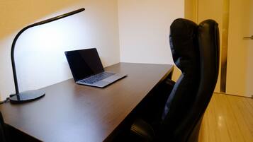 A wooden desk with a laptop and a black desk lamp.