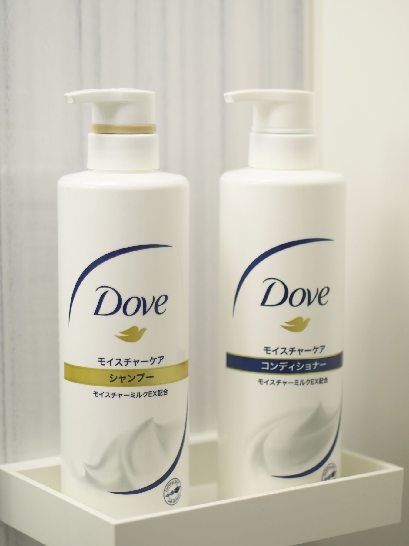 Two Dove personal care products on a white shelf.