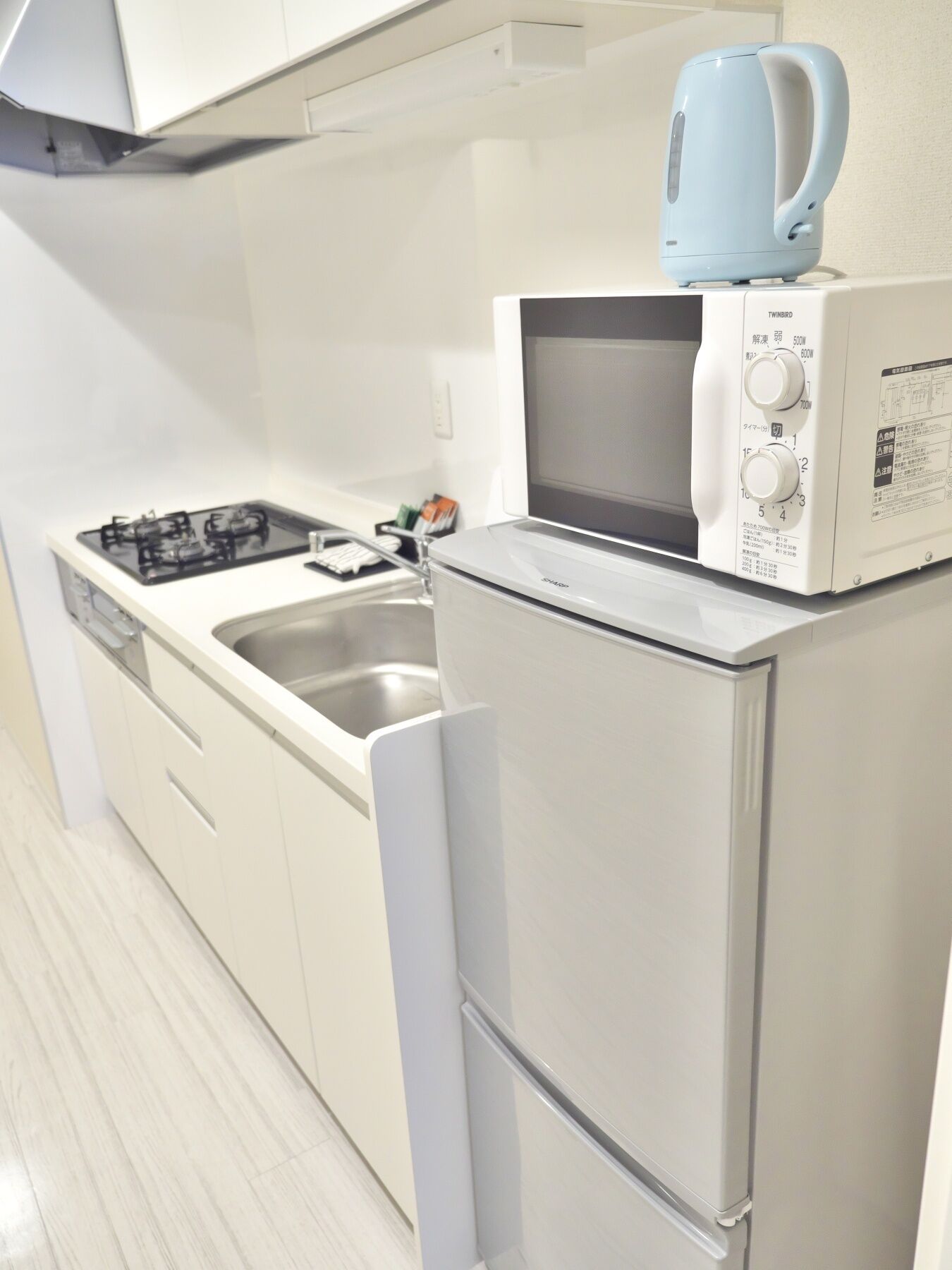 A compact kitchen with a gas stove, a microwave, and a built-in oven.