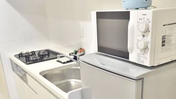 A compact kitchen with a gas stove, a microwave, and a built-in oven.