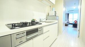 A modern kitchen with a gas stove, microwave, and built-in oven. - Kicon Hotels Fuchsia (Nagoya)
