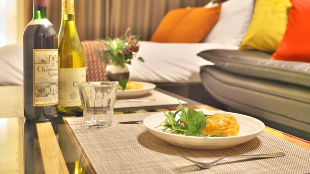 A dining table with a bottle of wine, a glass, and a plate of food. - Kicon Hotels Fuchsia (Nagoya)