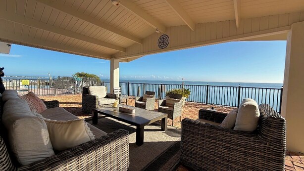 Una terrazza esterna con mobili in vimini, un tavolo e vista sul mare.