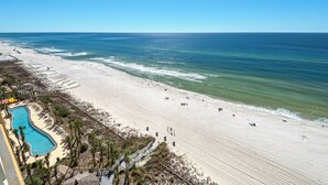 A beach resort with a swimming pool, beach chairs, and a lifeguard tower. - Calypso Resort by BBG (Panama City Beach)