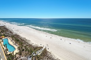 A beach resort with a swimming pool, beach chairs, and a lifeguard tower. - Calypso Resort by BBG (Panama City Beach)