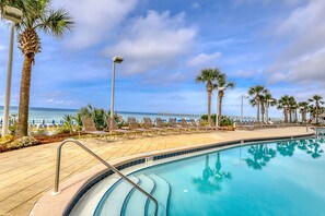 A poolside area with lounge chairs, palm trees, and a view of the ocean. - Calypso Resort by BBG (Panama City Beach)
