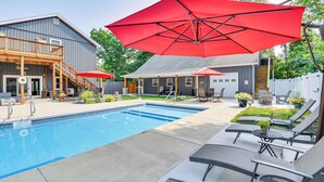 A backyard with a swimming pool, lounge chairs, and red umbrellas. - Benton Harbor Apt w/ Balcony + Fire Pit (Benton Harbor)