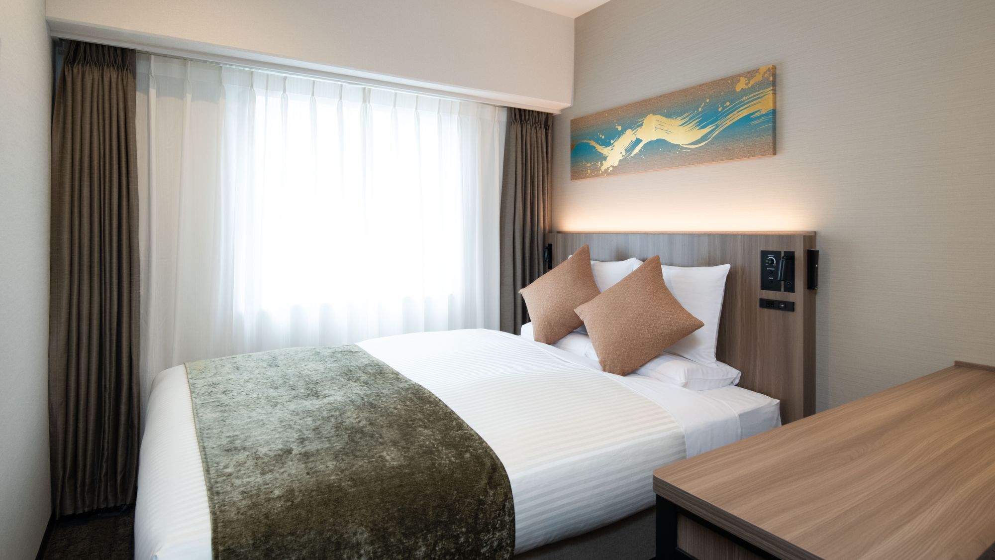 A hotel room with a bed, a bedside table, a painting on the wall, and curtains.
