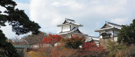 A traditional Japanese building with a tiled roof and white walls, surrounded by autumn foliage.