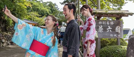 A traditional Japanese setting with people in kimonos, a stone pathway, and a sign with Japanese characters.